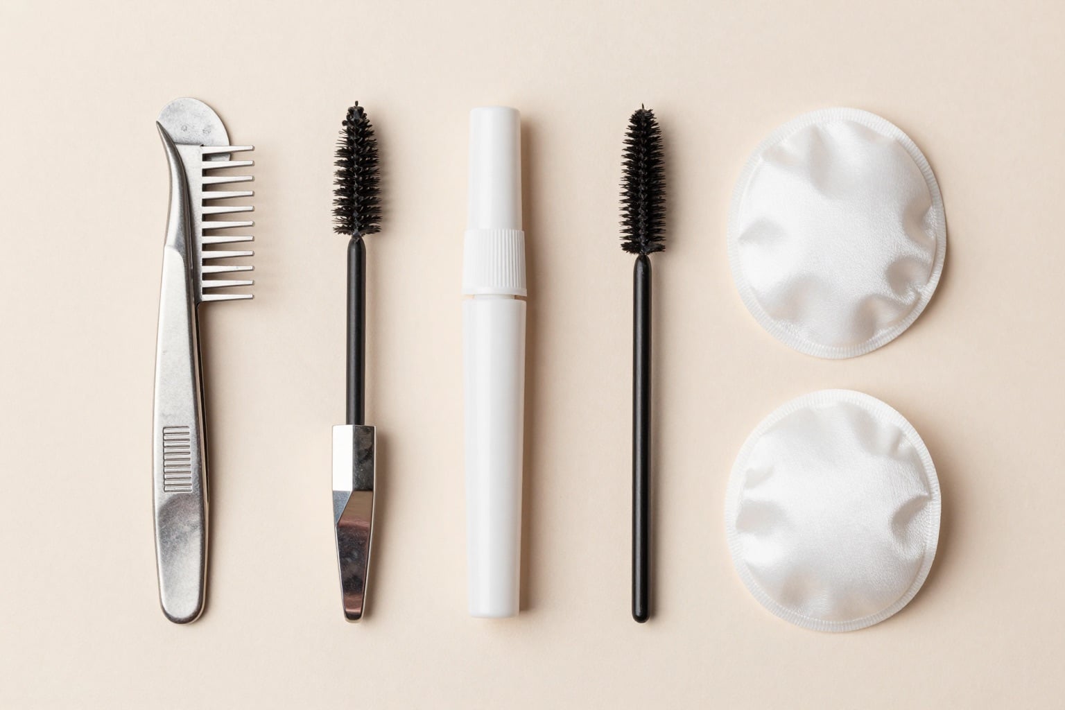 Flatlay mit Wimpern-Trays, Pinzette, Bürstchen und Pads auf pastellfarbenem Hintergrund