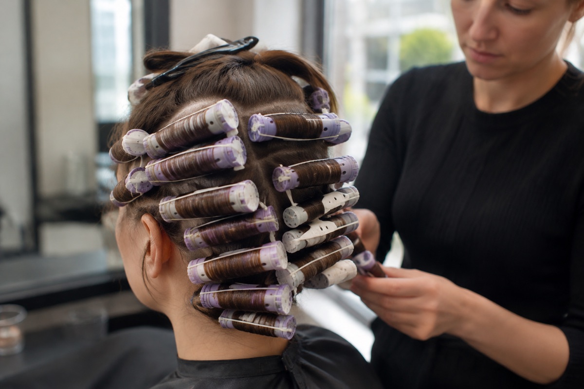 Friseurin dreht Lockenwickler für eine Dauerwelle ein