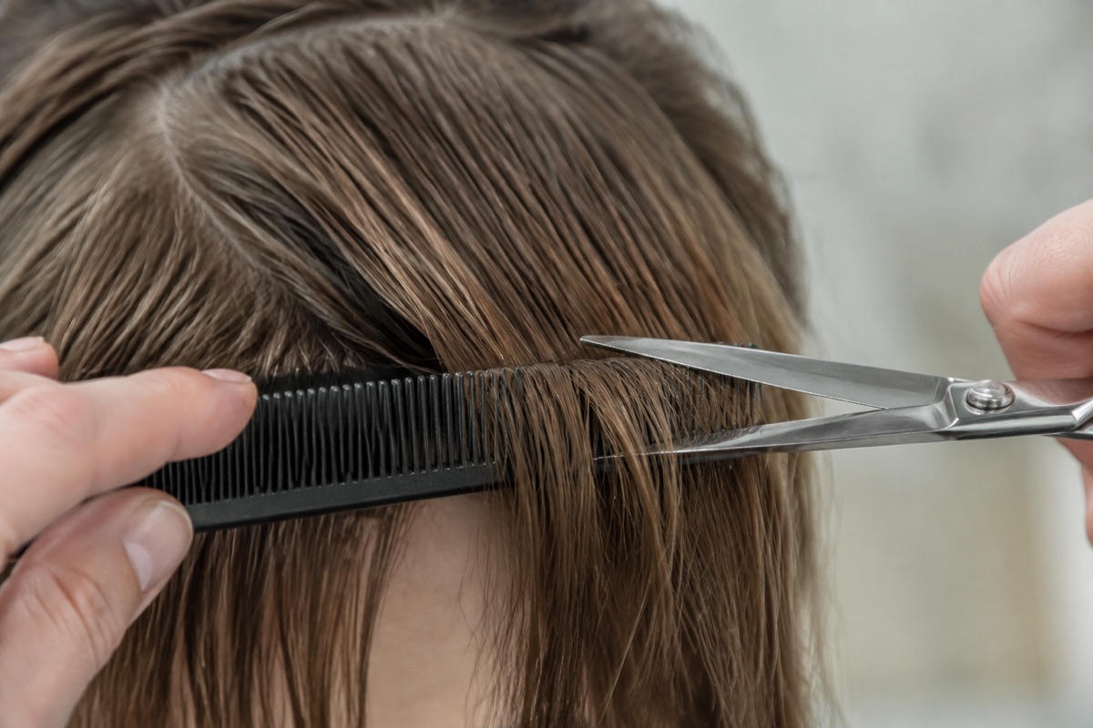 Abgeteilte Ponysträhne wird mit einer Friseurschere gekürzt