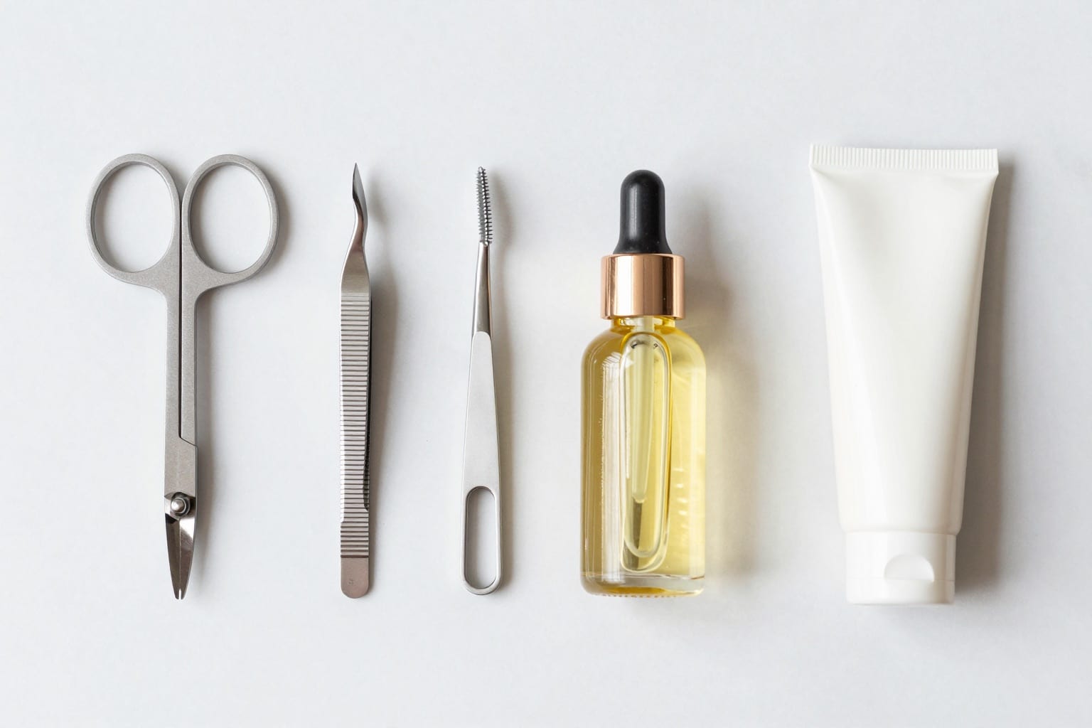 Flatlay eines Maniküre-Sets mit Schere, Knipser, Pinzette und Nagelöl auf Marmor