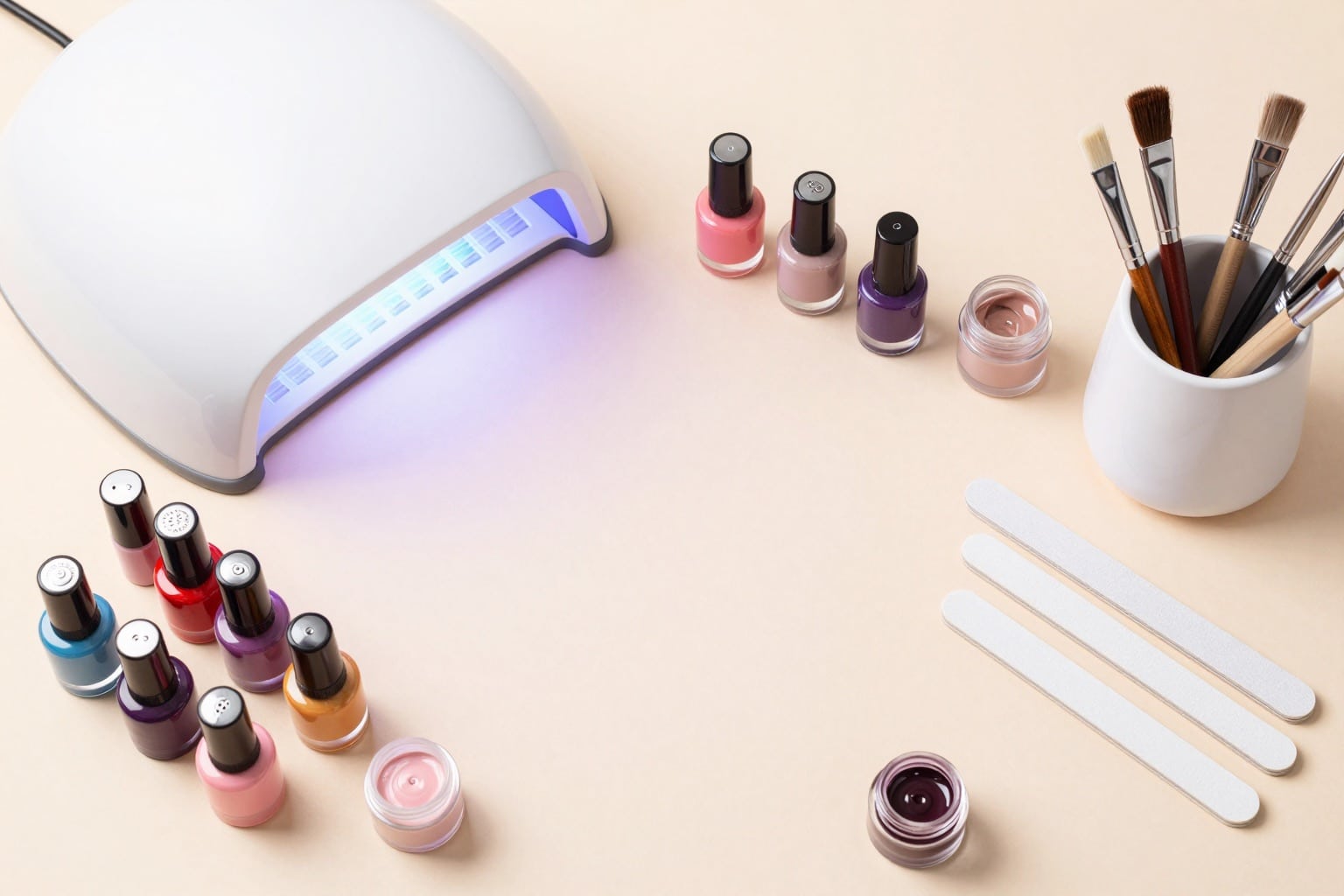 Nagelstudio-Equipment als Flatlay: Nagellacke, UV-Lampe, Feilen und Pinsel auf hellem Hintergrund